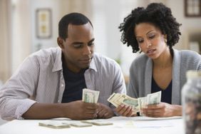 African American couple stressed counting money together at a table