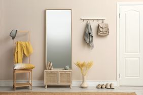 Organized entryway with light pink paint, mirror with bench, and wall hooks