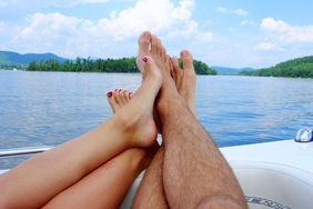 Couple with feet up on boat on water enjoying early retirement