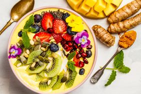What Is an Anti-Inflammatory Diet?: Mango banana pineapple turmeric breakfast superfoods smoothie bowl topped with fruits, berries and seeds