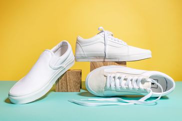 Three white tennis shoes on a yellow and teal background