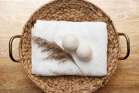 Natural wool dryer balls for more soft clothes while tumble drying in washing machine concept. Earthly tones, reed decoration. Discharge static electricity and shorten drying time, save energy.
