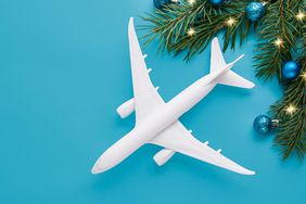 Christmas travel planning. Traveling as gift. White blank model of passenger plane and gift box on background. Top view or flat lay.