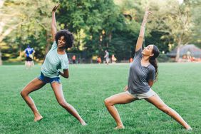 Two women doing yoga outside in a park