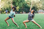 Two women doing yoga outside in a park