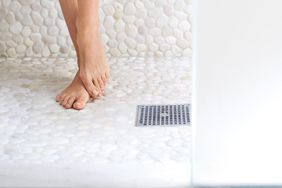 Woman standing in shower, cropped view of feet