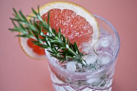 Gin and tonic with a slice of pink grapefruit and fresh herbs