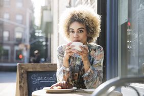 Woman sitting at an outdoor cafe drinking a cup of coffee