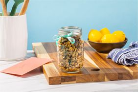 A glass gar full of granola and ribbon on a cutting board