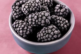Frozen blackberries in a bowl on pink background
