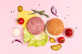 Ingredients of meat burger on pink background, flat lay, table top view