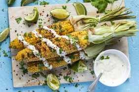 Grilled BBQ Corn Cob with Herbs, Lime and Garlic Sauce. Mexican Street Food or Summer Garden Party Snack