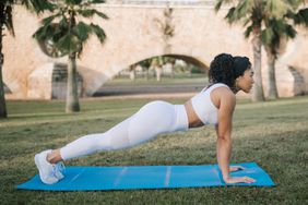 Young fit Black woman doing full push-ups exercise outside