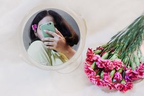 woman looking in mirror with flowers