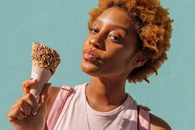 Portrait of young woman with ice cream cone at a wall