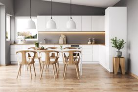 Kitchen featuring a white six-seater table, wooden chairs, and white sleek kitchen cabinets.