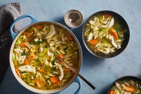 Chicken Noodle Soup, an easy make-ahead recipe, served in a Blue Cooking Pot With a Metal Ladle and Two Bowls of Soup on the Side