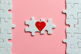 two pieces of a puzzle with red heart on pink background
