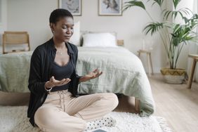 mindfulness-based stress reduction: young woman practicing mindfulness meditation on floor in bedroom