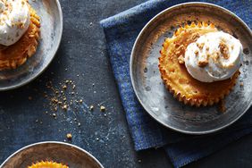 Mini pumpkin pies topped with whipped cream on a blue background