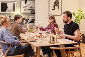 Family of four sitting around a table eating dinner; Scene from TV show Love & Anarchy