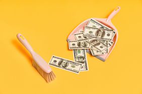 Creative layout with dustpan, hand brooms and money dollar bills on red background