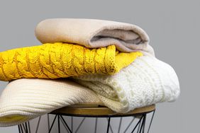 Stack of Trendy Bright illuminating Yellow, Gray and White Woolen Knitted Sweaters.