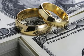 10 Important Things Every Couple Should Do Before Getting Married: gold wedding rings stacked on top of money
