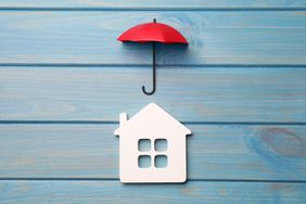 Small umbrella and house figure on light blue wooden