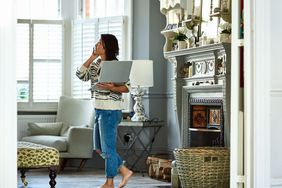 working-from-home-permanently: woman holding a laptop and talking on the phone at home